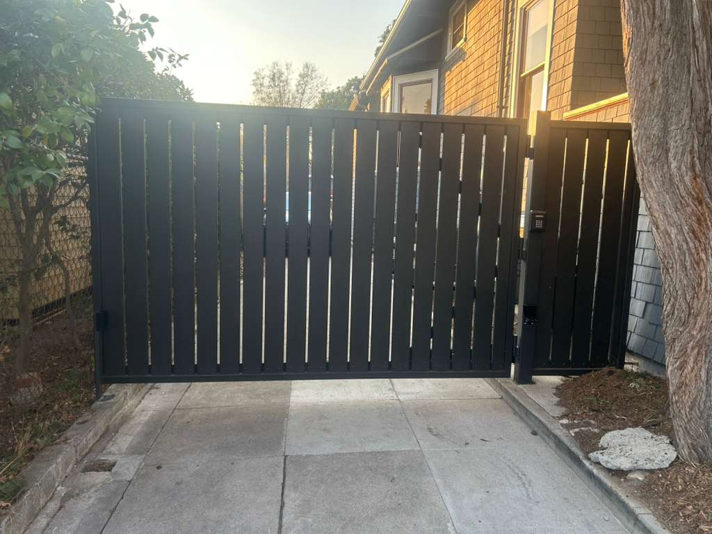 Modern dark gray metal gate with vertical slats and keypad access. in Westwood, CA